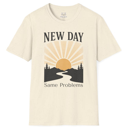 Beige t-shirt with a graphic design of a sun rising over a road flanked by trees and text 'New Day, Same Problems' on a white background.