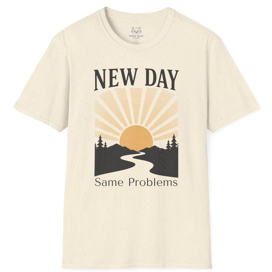 Beige t-shirt with a graphic design of a sun rising over a road flanked by trees and text 'New Day, Same Problems' on a white background.