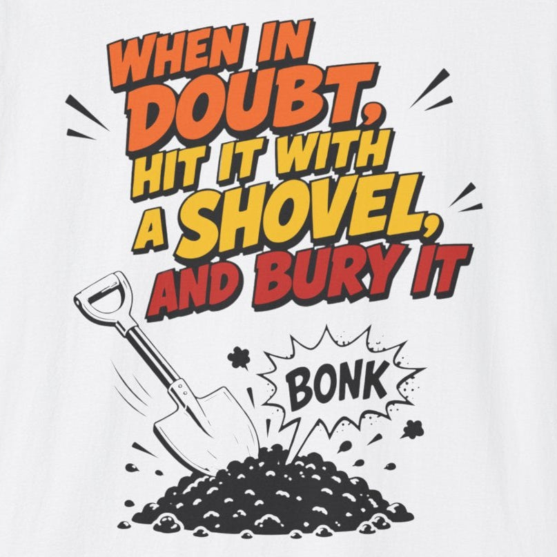 A white t-shirt featuring a bold graphic print on the front. The graphic displays the text 'WHEN IN DOUBT, HIT IT WITH A SHOVEL AND BURY IT' in orange and yellow comic-style lettering, accompanied by a black-and-white illustration of a shovel digging up dirt with a 'BONK' sound effect.