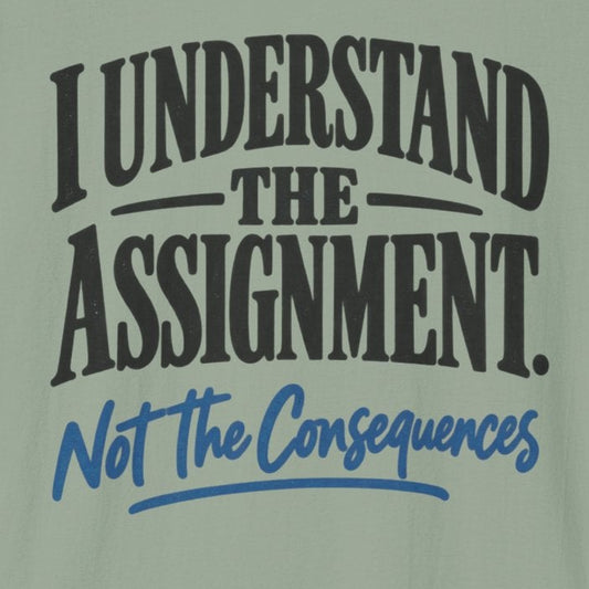 A sage green short-sleeve t-shirt with a graphic print on the front that reads 'I UNDERSTAND THE ASSIGNMENT. Not The Consequences' in black and blue lettering