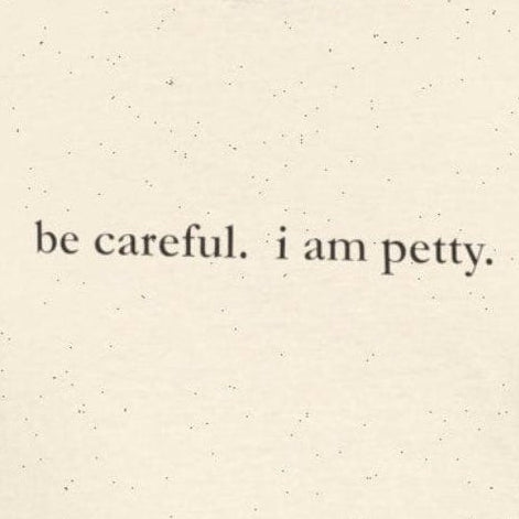 Person wearing cream t-shirt with 'be careful. i am petty" small, black text.