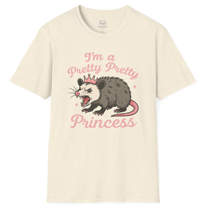 Cream t-shirt with an angry opossum wearing a tiara graphic and 'I'm a pretty pretty princess' pink text.